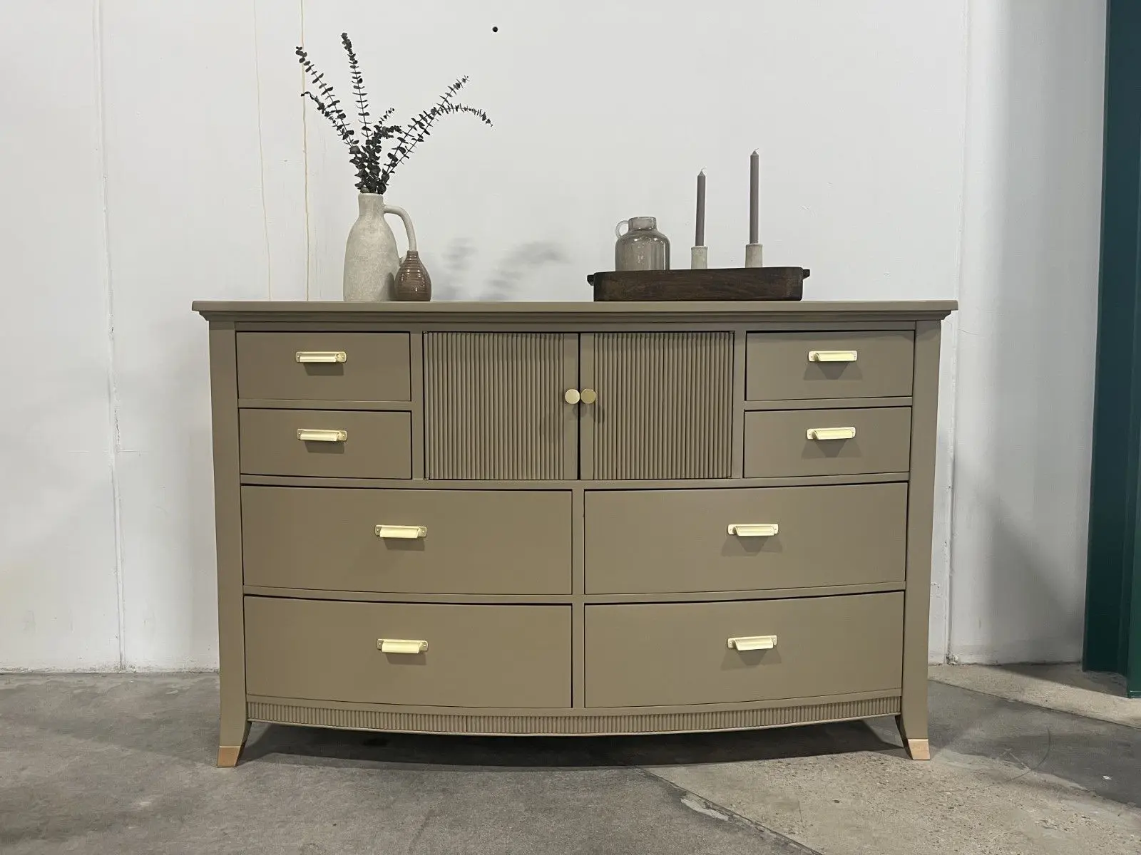A dresser with many drawers and a small vase
