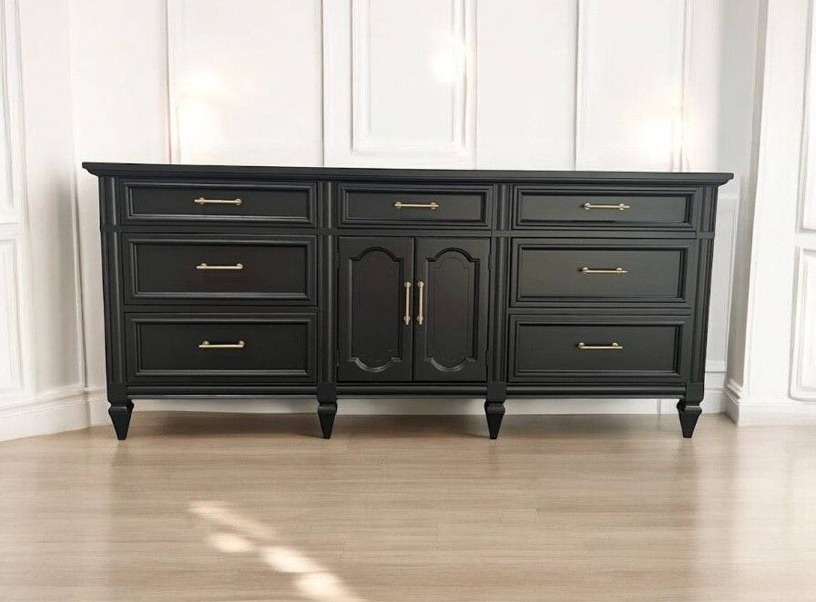 A black dresser with gold handles and knobs.