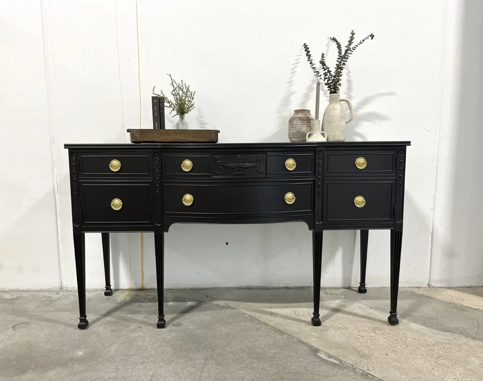 A black dresser with gold handles and two drawers.