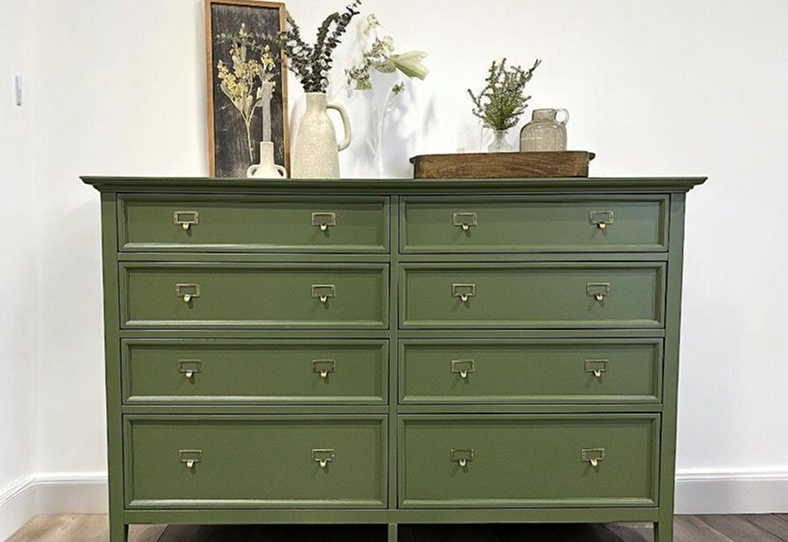 image 42 (1) A green dresser with eight drawers and a vase of flowers.