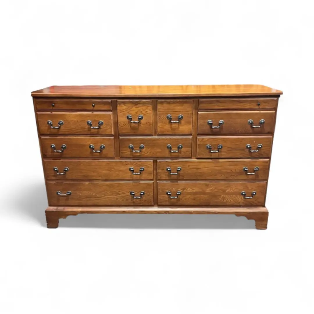 Wooden dresser with multiple drawers and handles.