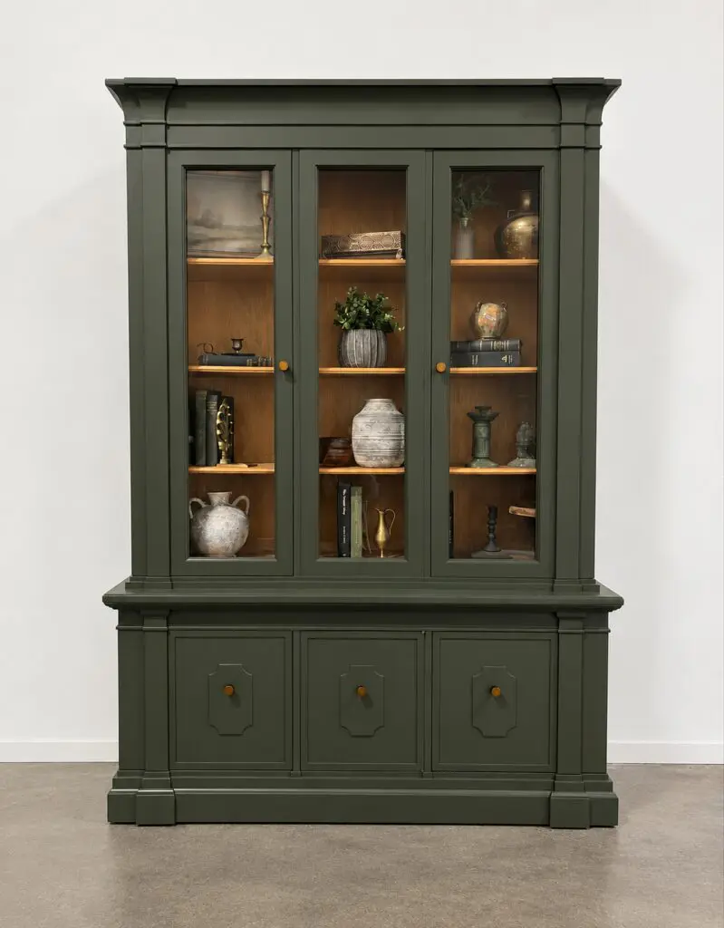 Green glass-front display cabinet with decor