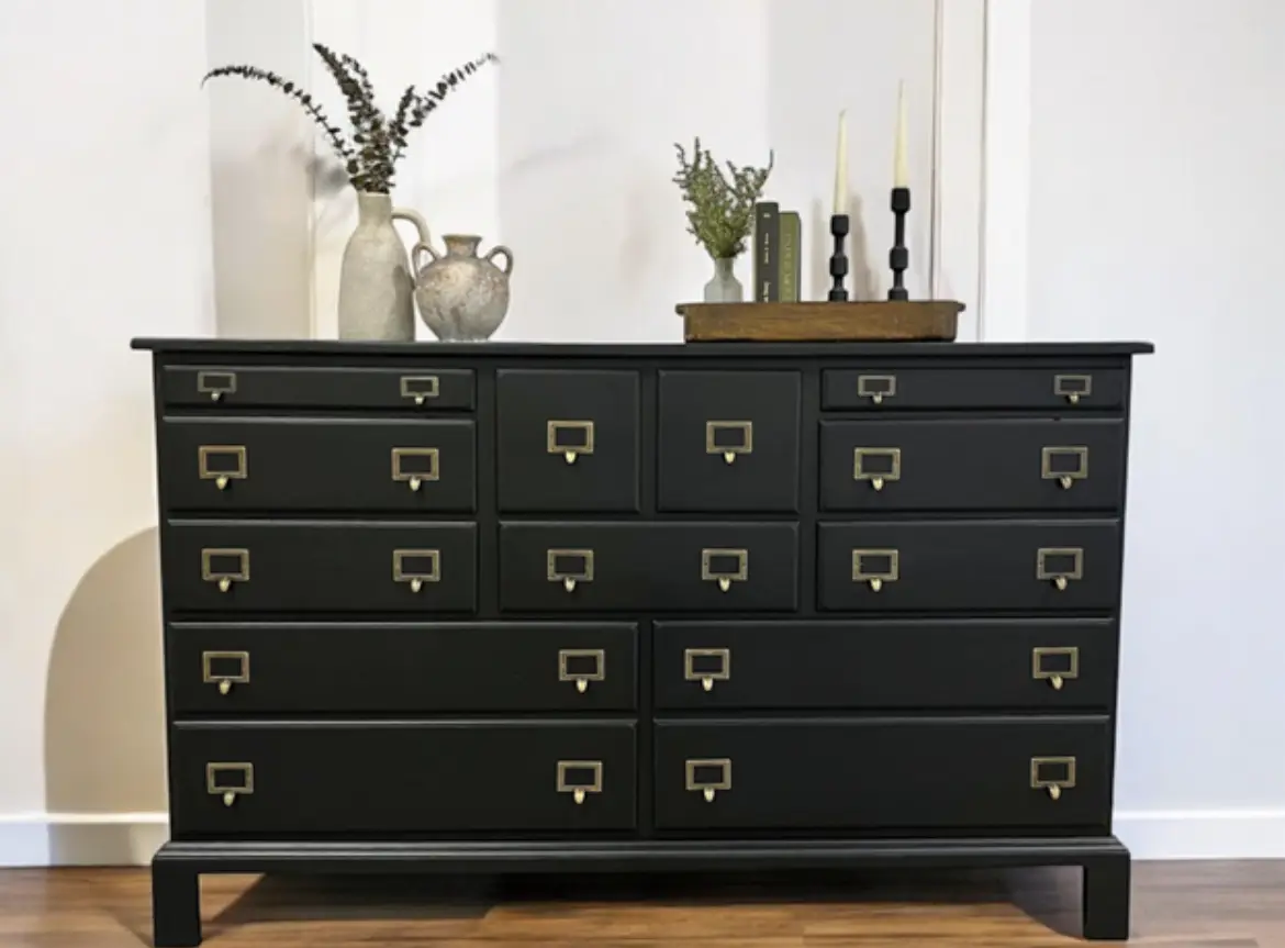 A black dresser with brass handles and knobs.